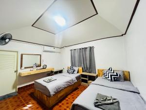 two beds in a room with a sink and a mirror at Lungwang Guest House in Ban Rak Thai