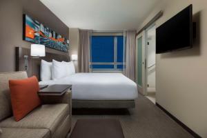 Hyatt Place New York City/Times Square في نيويورك: غرفه فندقيه بسرير واريكه