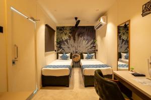 MundraClick Hotel Mundra的有两张床和一张书桌的酒店房间