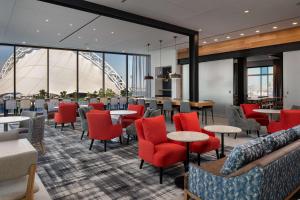 a restaurant with red chairs and tables and a view of the wheel at Hyatt Place Boston/Seaport District in Boston