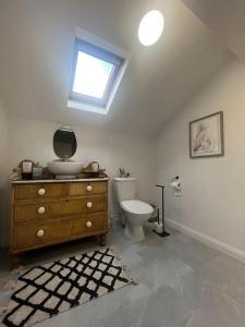 a bathroom with a toilet and a dresser with a window at Tynwald Apartments in Douglas