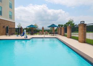 a large swimming pool with blue umbrellas and tables at Hyatt Place Austin Lake Travis/Four Points in Austin