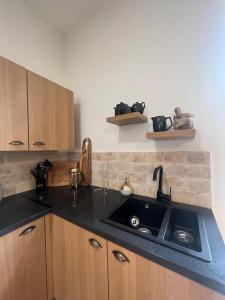 a kitchen with a black sink and wooden cabinets at Tynwald Apartments in Douglas