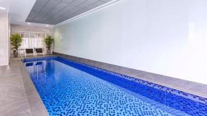 a large swimming pool with blue water in a room at Penthouse Sky View Apartment CBD 2BR Apartment with Balcony in Adelaide