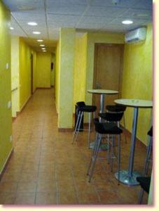 un corridoio con tavoli e sgabelli in una stanza di Llagotel a La Llagosta