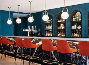 um bar com cadeiras laranja e uma parede azul em Hyatt Regency London Stratford em Londres