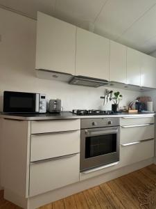 eine Küche mit weißen Schränken, einer Mikrowelle und einem Herd in der Unterkunft Anna in Aalborg