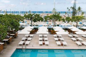 a hotel pool with white lounge chairs and a marina at Hilton Vacation Club The Modern Honolulu in Honolulu