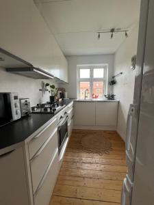 uma cozinha com electrodomésticos brancos e piso em madeira em Anna em Aalborg