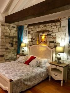 una camera con un grande letto e un muro di pietra di VİA PERLA BUTİK OTEL a Çiftlikköyü