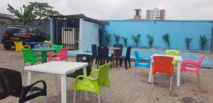 een groep kleurrijke tafels en stoelen voor een gebouw bij Explorez le charme et élégance de MMEWEL HÔTEL in Douala