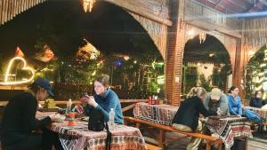 a group of people sitting at tables in a restaurant at Trang An Quynh Trang Happy Homestay & Garden in Ninh Binh