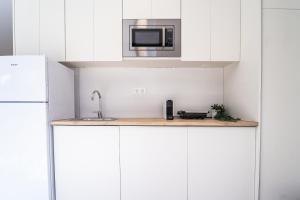 a kitchen with white cabinets and a microwave at Ca la Mar Villajoyosa in Villajoyosa