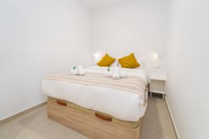 a bedroom with a bed with white sheets and yellow pillows at Ca la Mar Villajoyosa in Villajoyosa