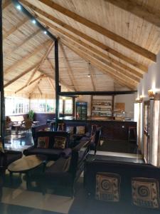 Großes Zimmer mit Stühlen und einer Decke mit Balken in der Unterkunft Ngorongoro Camp and Lodge in Karatu