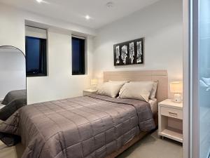 a bedroom with a bed and two lamps and windows at CBD Sky View Apartment in Adelaide
