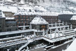 a building covered in snow in a city at Hotel Val de Neu G.L. in Baqueira-Beret