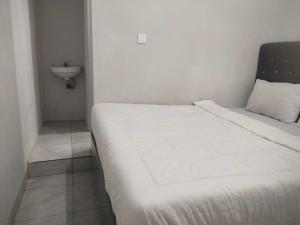 białe łóżko w niewielkim pokoju z umywalką w obiekcie OYO 1067 Villa Sofia At Silang w mieście Tagaytay