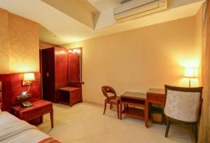 アーメダバードにあるHOTEL RK REGENCYのデスクとベッドが備わるホテルルームです。