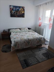 a bedroom with a bed with a comforter and a rug at Apartament Alex in Alba Iulia