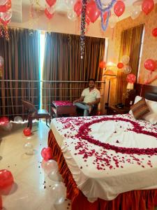 a man sitting in a room with a large bed with balloons at HOTEL RK REGENCY in Ahmedabad