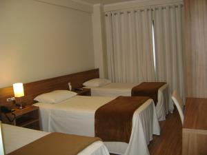 a hotel room with two beds and a window at Hotel Areias Brancas in Rosário do Sul