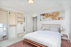 a white bedroom with a bed and a painting on the wall at Vivid house in Wembley Downs in Perth