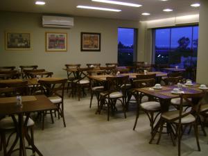 a dining room with tables and chairs and a large window at Hotel Areias Brancas in Rosário do Sul