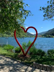 a red heart statue on the side of a lake at Haus Feldseeblick in Feld am See