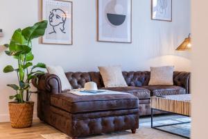 sala de estar con sofá de cuero marrón y reposapiés en Renovated 2-bedroom apartment 10min to the Palais en Cannes