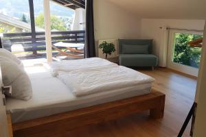 een slaapkamer met een bed, een stoel en een raam bij Moderne Ferienwohnung mit großem Balkon in Aschau im Chiemgau