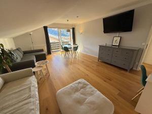 a living room with a couch and a tv and a table at Moderne Ferienwohnung mit großem Balkon in Aschau im Chiemgau