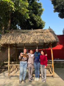 a group of people standing in front of a thatch hut at The Garden Homestay Ninh Bình in Ninh Binh