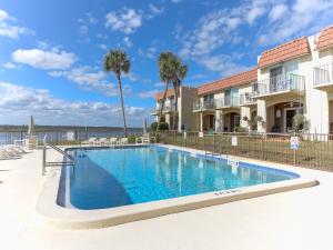 a swimming pool in front of a building with palm trees at Point Matanzas B3 in St. Augustine