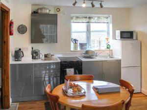 a kitchen with a table and a white refrigerator at Daisy Apartment in Stalham