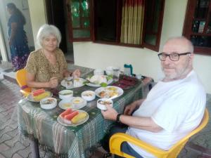 un uomo e una donna più grandi seduti a un tavolo con del cibo di Dinimuthu Rest Inn a Wellawaya