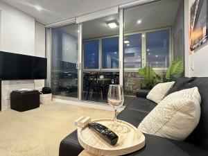 a living room with a couch and a glass of wine at CBD Sky View Apartment in Adelaide