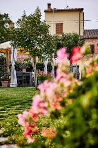 a garden with pink flowers in front of a house at La Piccola Loggia in Torrita di Siena