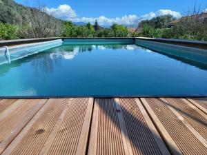 a swimming pool with a wooden deck and blue water at L'AMANDIER -LE FIGUIER-LES LAURIERS ROSES in Ajaccio