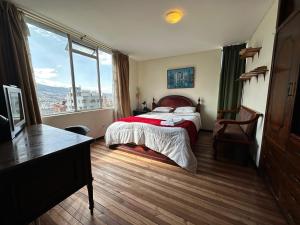een slaapkamer met een bed en een groot raam bij St. Gallen Haus in Quito