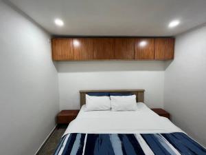 - une chambre avec un lit blanc et une armoire en bois dans l'établissement Lx Apart in Sommerschield 2, à Maputo