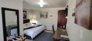 una camera d'albergo con letto e specchio di Premiere Guesthouse a Bloemfontein