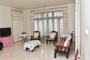 a living room with chairs and a flat screen tv at MAHAMAYA HOME STAY in Mysore
