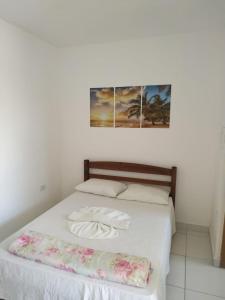 a bedroom with a bed with two pictures on the wall at Pousada Peruíbe Frente ao Mar - Suítes, Kitnets e Apto in Peruíbe +7 photos