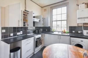 a kitchen with white cabinets and black counter tops at Keysan House 5 in London