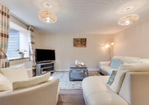 a living room with white furniture and a flat screen tv at Ardley Cottages in Waldingfield