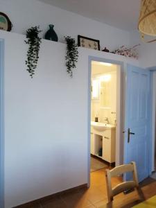 a room with a white wall and a chair and a bathroom at Aegina Port Apt 2-Διαμέρισμα στο λιμάνι της Αίγινας 2 in Aegina Town