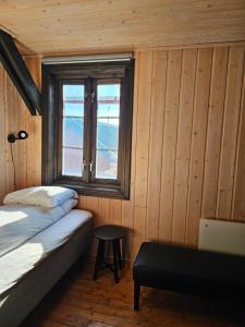 1 dormitorio con cama, ventana y taburete en Salteriet en Å