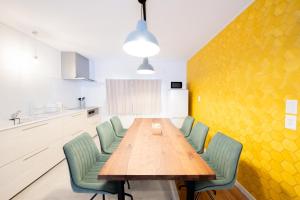 a dining room with a wooden table and green chairs at Furano Powder Chalet in Furano