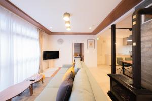 a living room with a couch and a tv at Furano Powder Chalet in Furano